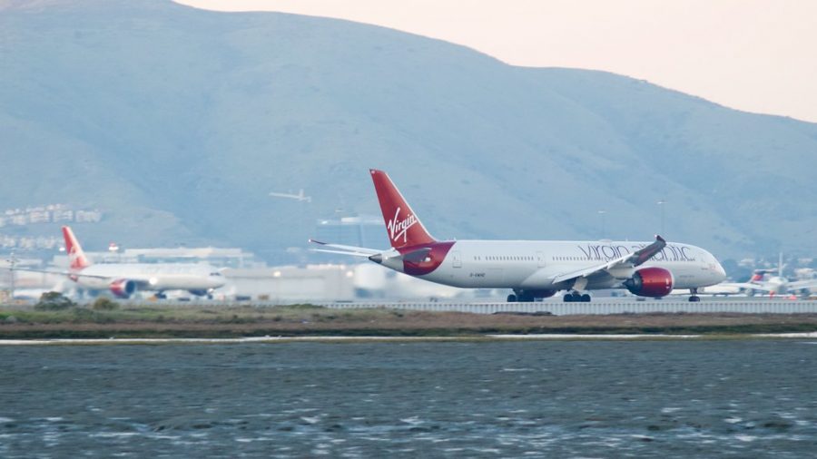 Two Virgins, a pair of Boeing 787 -9 twin aisle passenger planes G-VWHO is taking off, G-VCRU has landed and is taxiing in. DSC_0255 by wbaiv is licensed under CC BY-SA 2.0